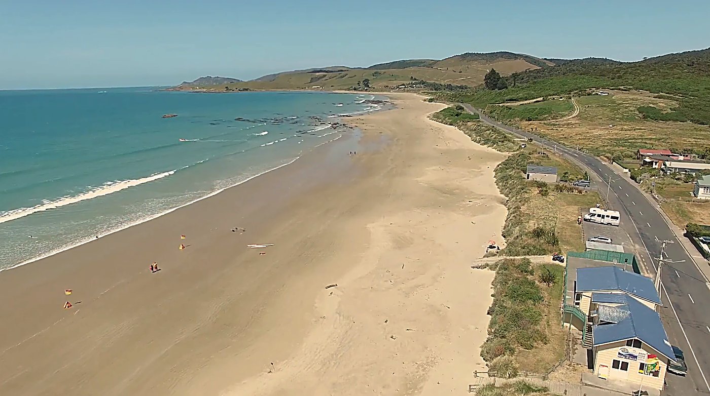 The patrolled beach below the dunes, the surf club and flags out on a warm Catlins day, Kaka Pt surf spot, Catlins / Southlan